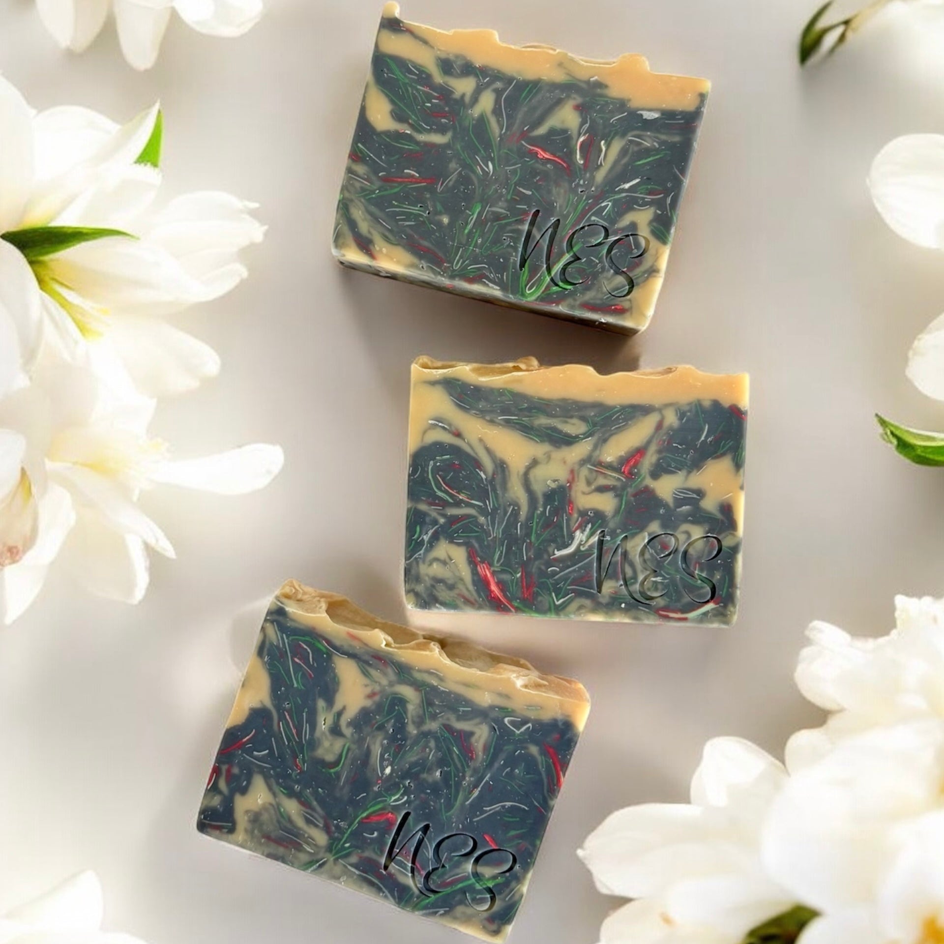 NES Midnight Bloom artisan soap bar surrounded by white flowers - scented with bergamot, gardenia, jasmine and sandalwood.