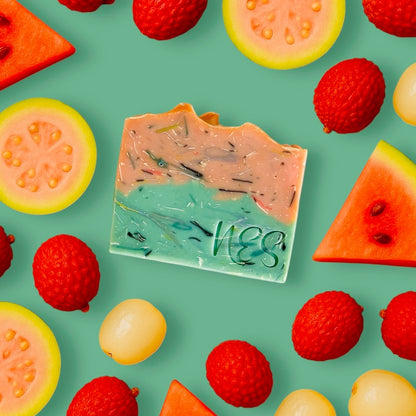NES Fruit Pop artisan soap surrounded by watermelon, lychee, and guava on green background – vibrant vegan soap inspired by summer fruits