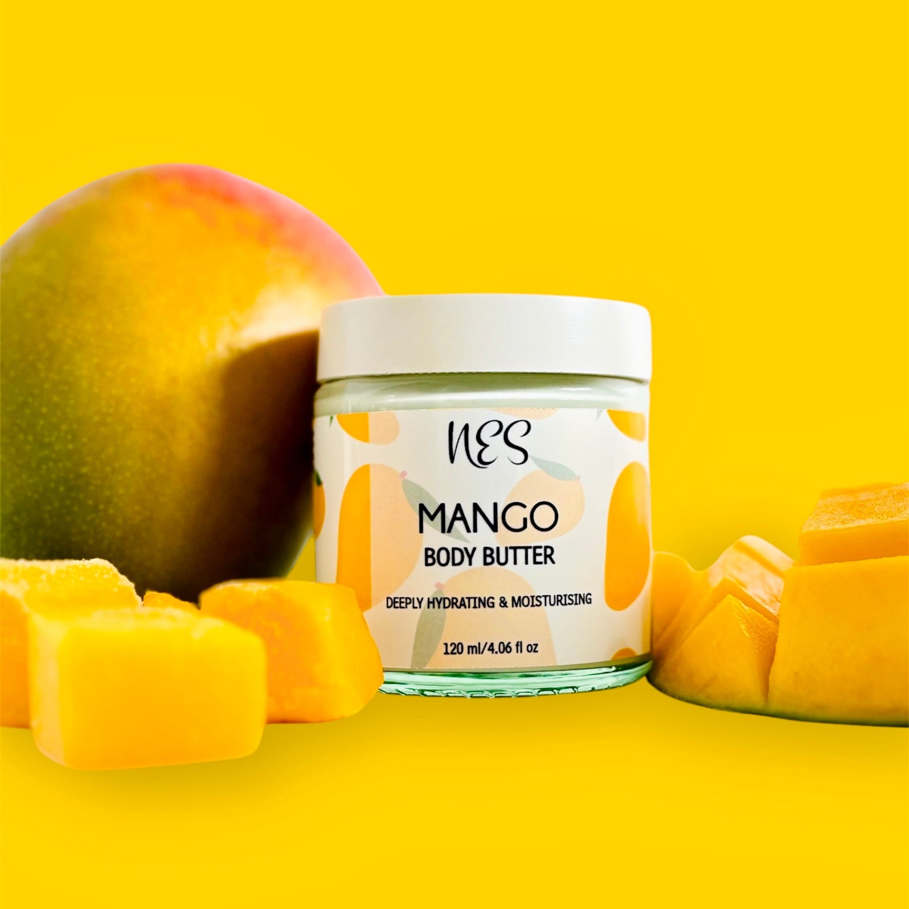 NES Mango Body Butter in a glass jar, surrounded by fresh mango and mango cubes. Vegan, deeply hydrating skincare made with shea butter and vitamin E – NES Soap NZ.