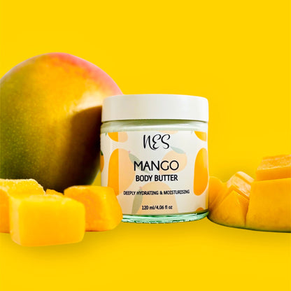 NES Mango Body Butter in a glass jar, surrounded by fresh mango and mango cubes. Vegan, deeply hydrating skincare made with shea butter and vitamin E – NES Soap NZ.