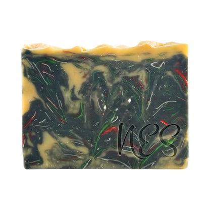 Close-up of NES Midnight Bloom handmade soap showing its dark floral swirl design with hints of gold and red.
