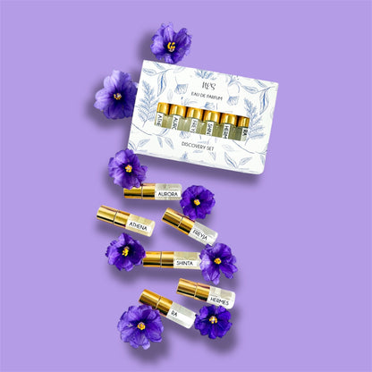 NES Soap Discovery Set – a collection of six luxury Eau de Parfum samples with gold spray caps, beautifully arranged with purple flowers. Vegan, cruelty-free fragrances from NES Soap NZ.